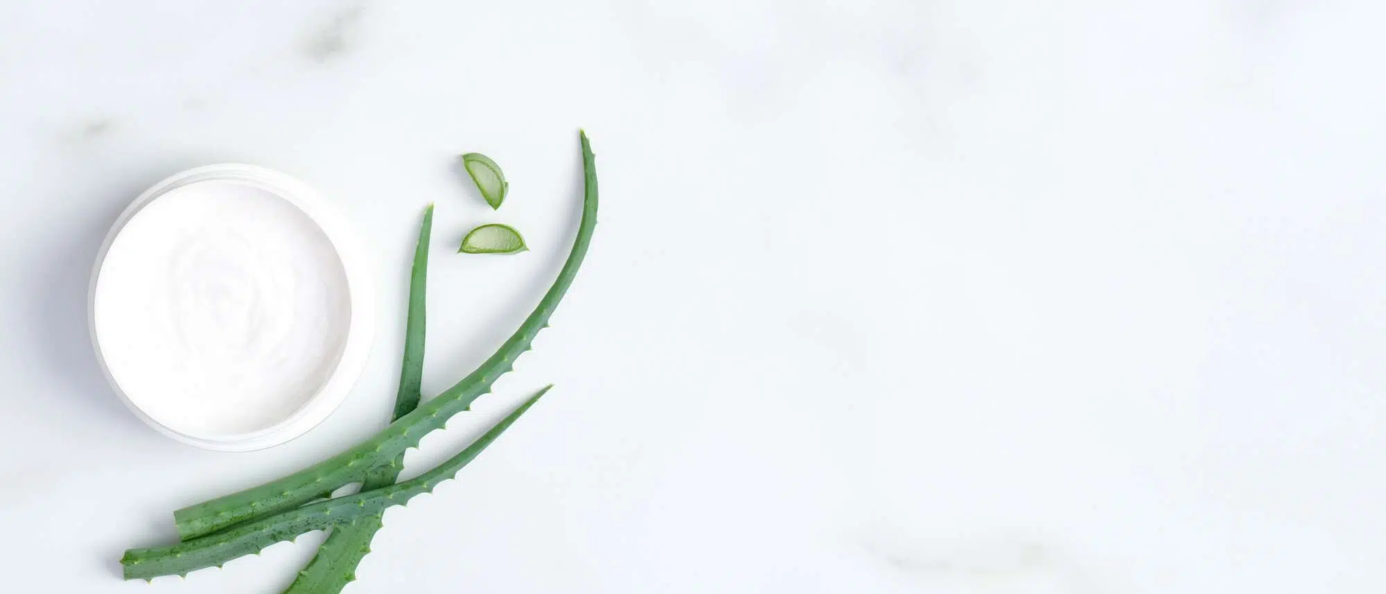 Natural Cosmetic Skincare Moisturizer Cream Jar And Sliced Stems Aloe Vera On Marble Background. Flat Lay, Top View. Skin Care And Beauty Treatment Concept.